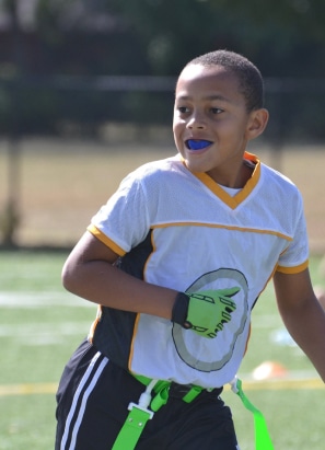 Young child playing sports showcasing mouthguard for protection.
